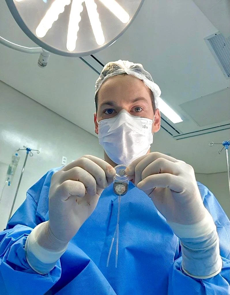 Doutor Bruno Taguchi, Médico Otorrino, segurando um implante coclear em seu consultório em Campo Grande MS.